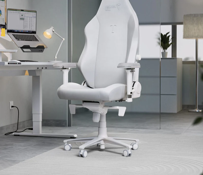 Real photo of a white Secretlab chair at a standing desk with a laptop, desk lamp and plant, in a home office setup (mirrored, cropped)